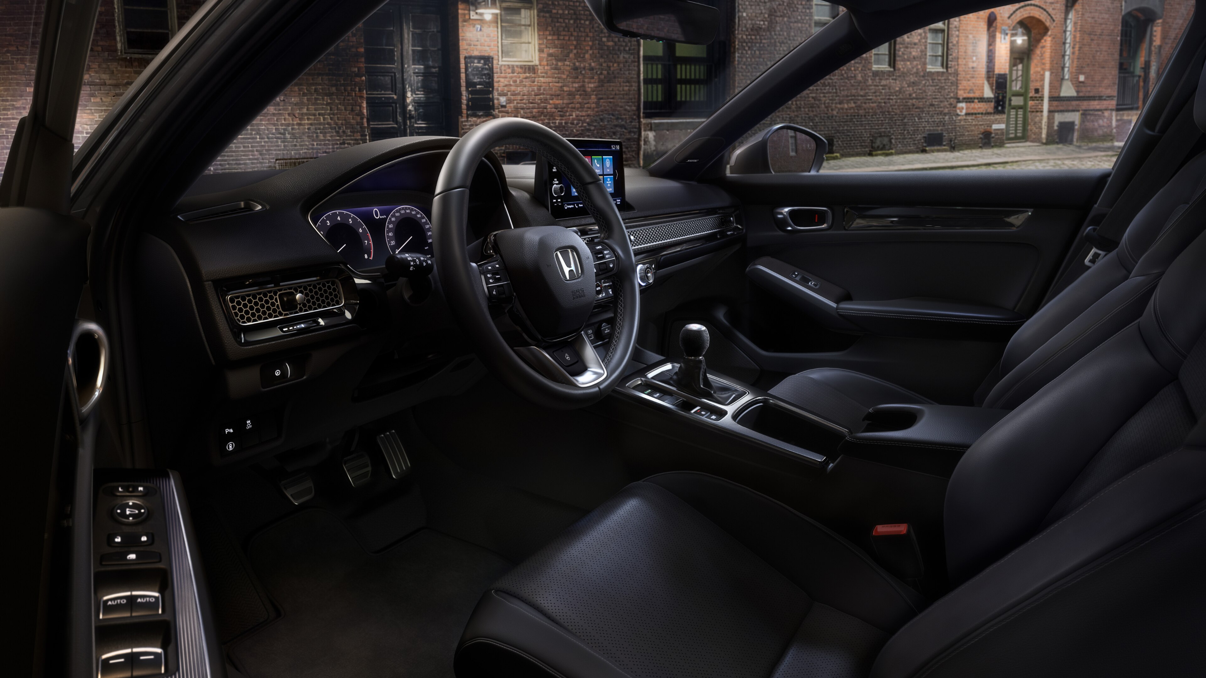 View of Honda Civic Hatchback driver's seat and console through an open driver side door