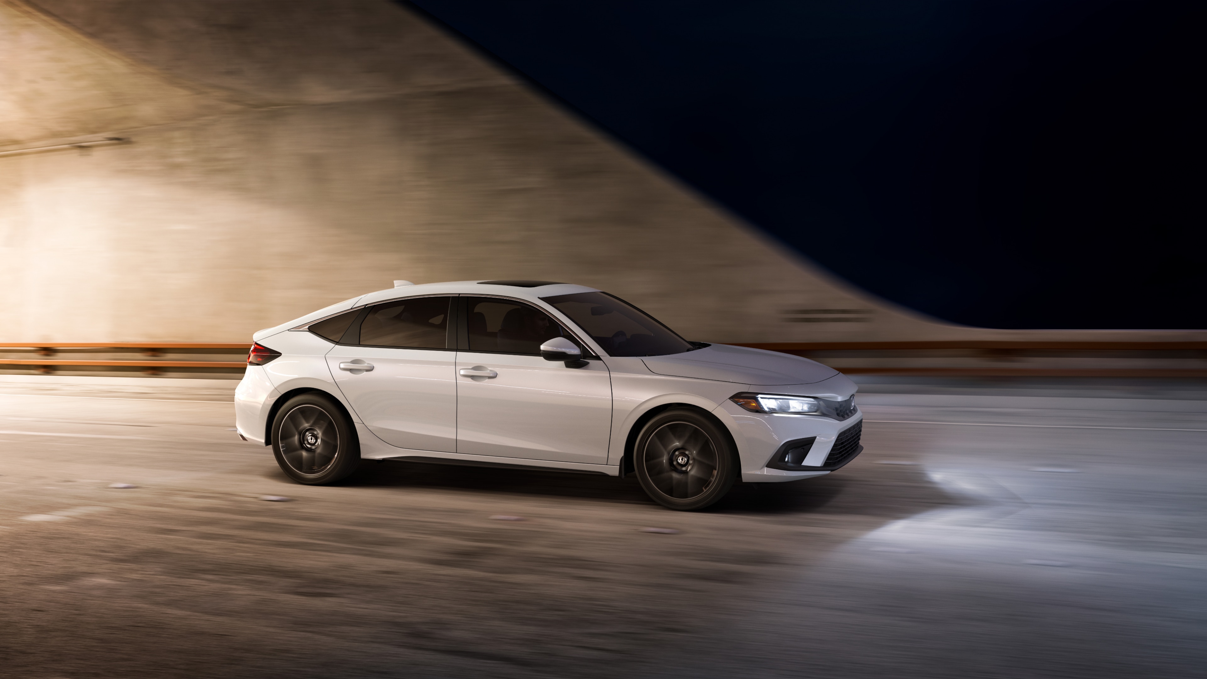 Side view of white Honda Civic Hatchback leaving a well-lit tunnel at night