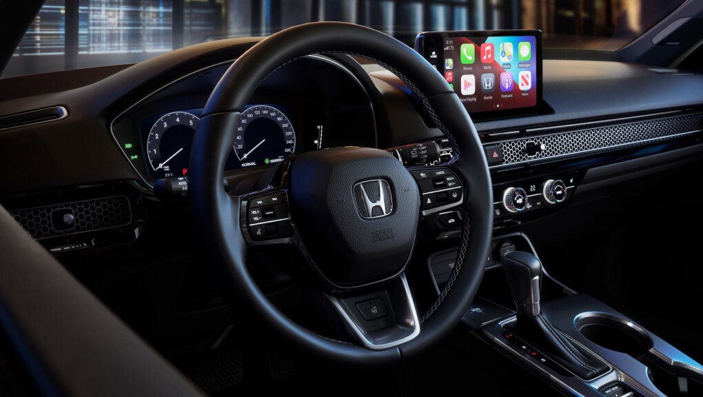 View of Honda Civic Hatchback driver's seat and console through an open driver side door