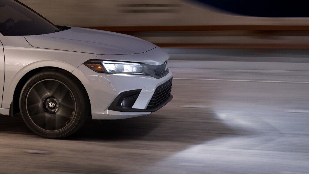 Side view of white Honda Civic Hatchback leaving a well-lit tunnel at night