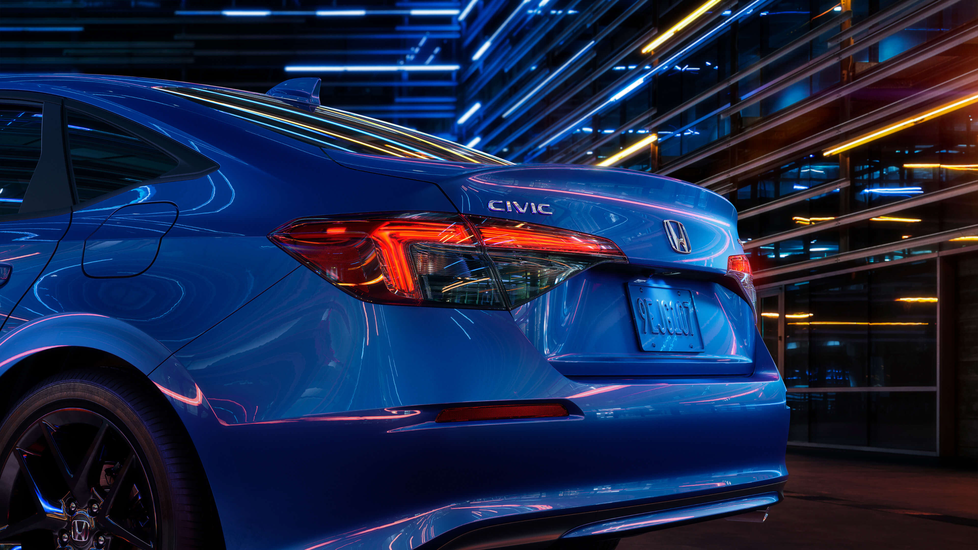 Vue arrière latérale en angle d’une Honda Civic 2022 bleue, de nuit, dans une ville.