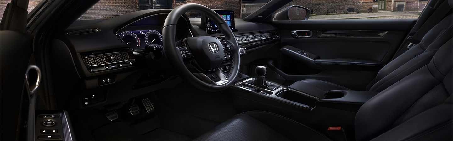 Interior view from Honda Civic Hatchback driver's seat looking out to a brick building.
