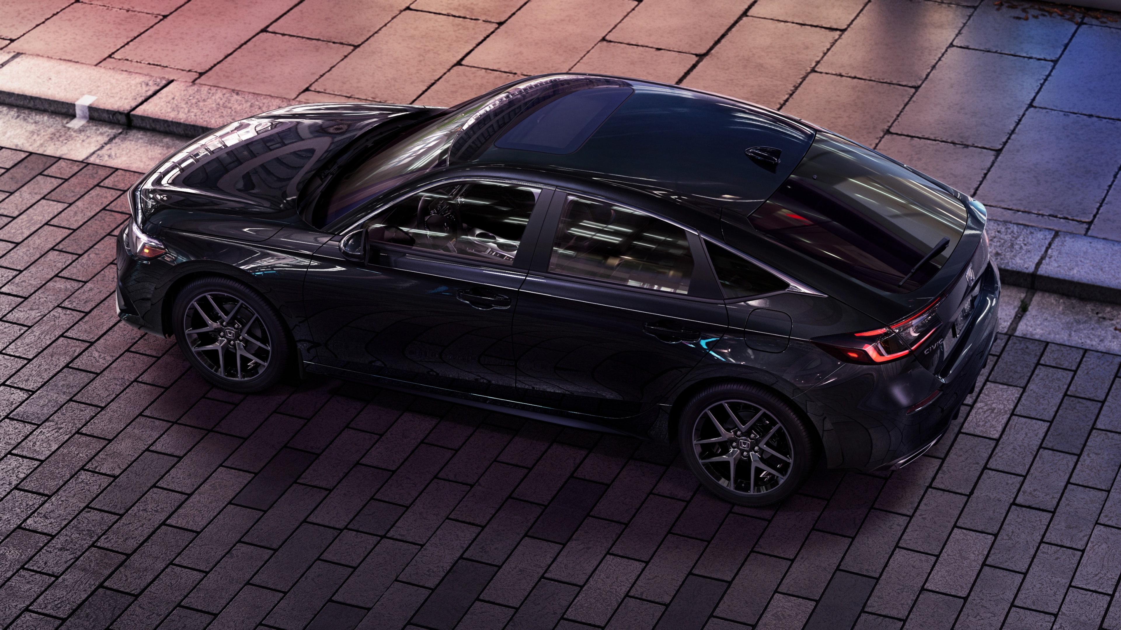 Overhead side view of black Honda Civic Hatchback parked at a curb on a brick road.