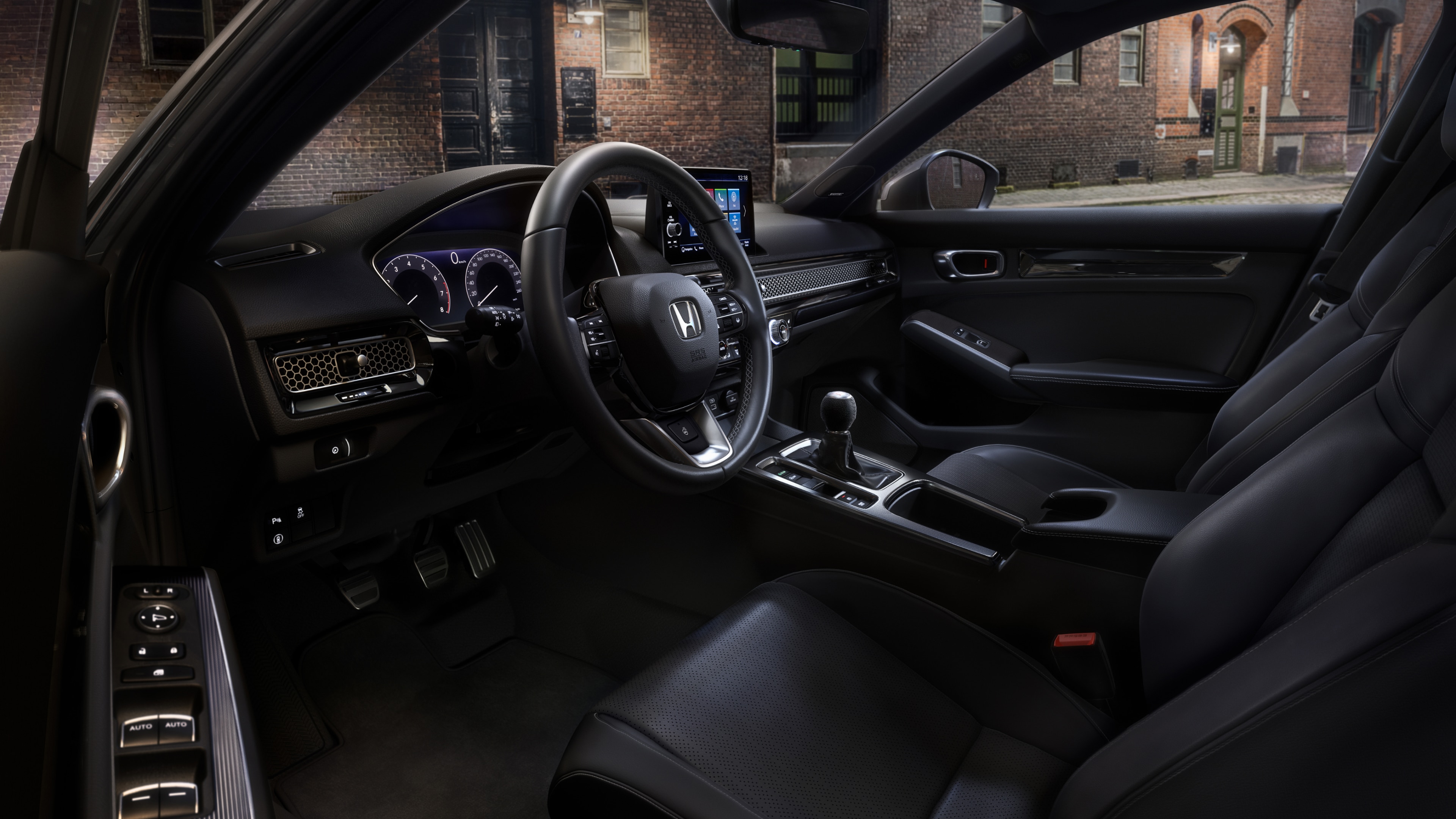 View of Honda Civic Hatchback driver's seat and console through an open driver side door