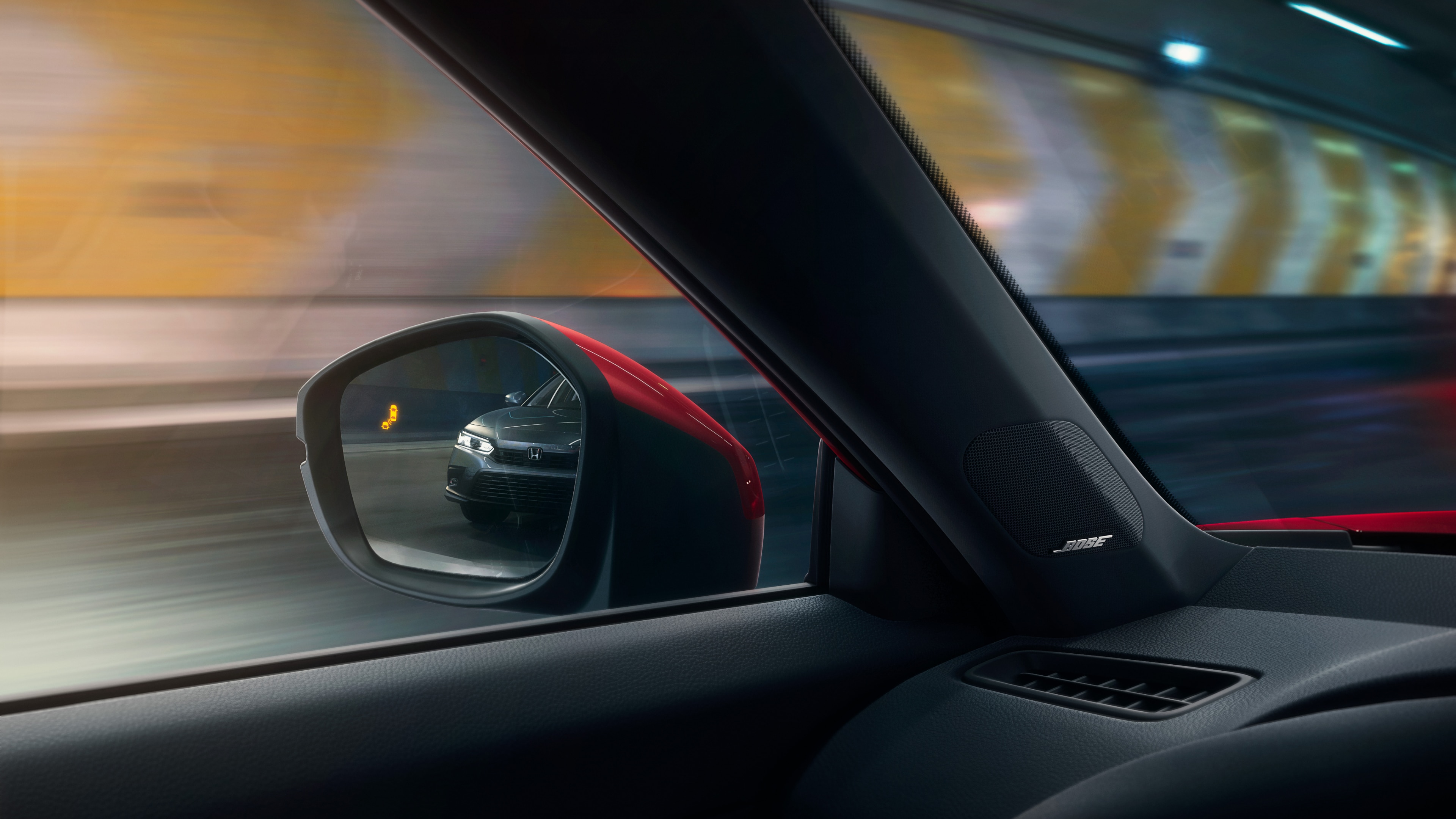 View from red Honda Civic Hatchback driver’s seat of a black car reflected in the side mirror